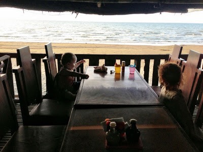 sitting at a restaurant table at seafood shacks with baybay beach in the background, roxas city with kids