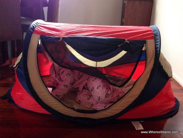 Toddler lying down in travel crib