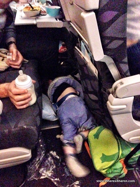 infant having a tantrum on the plane on the floor in front of the seats