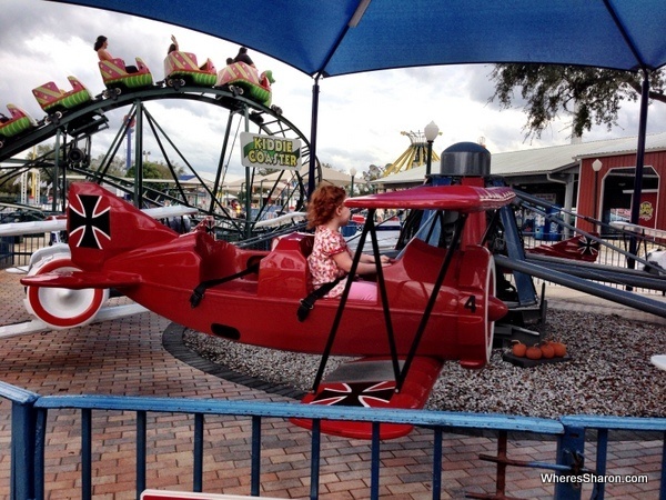 S flying in plane with a roller coaster in the background at fun spot usa