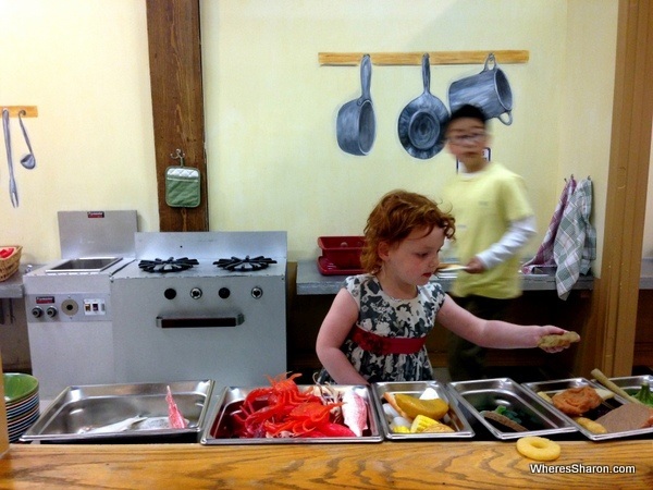 Kid using plastic food to make food with toy oven in louisiana's children museum