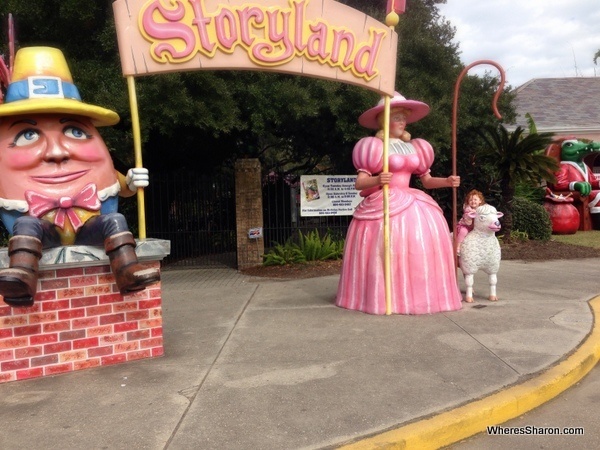 S sitting on lamb with big sign saying story land