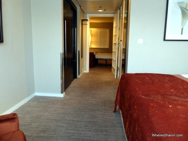 Looking from the main bedroom to the hall/cupboard area to the living room